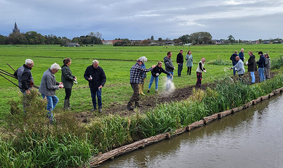 Mensen van het agrarisch collectief Noord Holland, gemeenten, het waterschap en de provincie zaaien symbolisch een van de nieuw aangelegde oevers in voor bloemrijk grasland