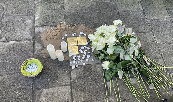 De 3 struikelstenen voor Jacob, Helena en Leo Snijders, met brandende kaarsen, steentjes en witte rozen